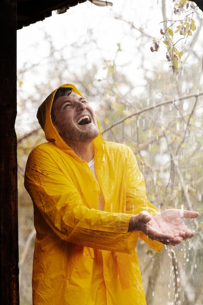 Foto gratuita ritratto di pioggia di giovane uomo in impermeabile