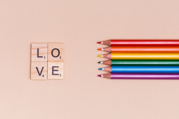 Rainbow colorful pencils and LOVE letters on beige background