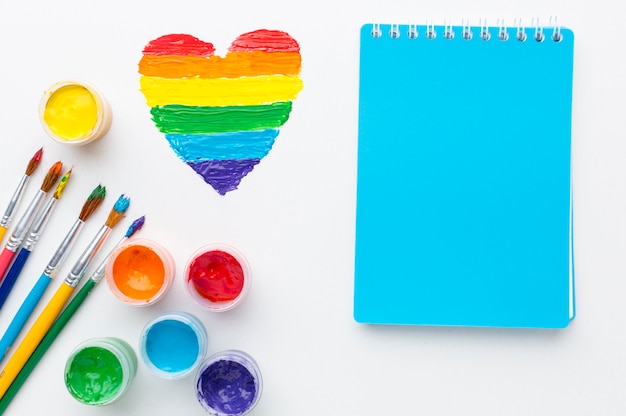 Rainbow containers of paint for pride love and notepad