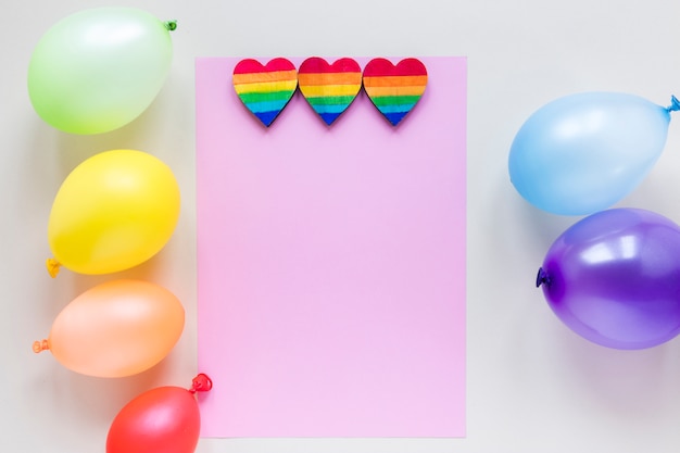 Free photo rainbow hearts with paper and air balloons