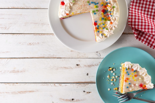 Rainbow layer cake on white wooden table