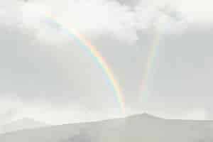 無料写真 雲と山の背景の上の虹
