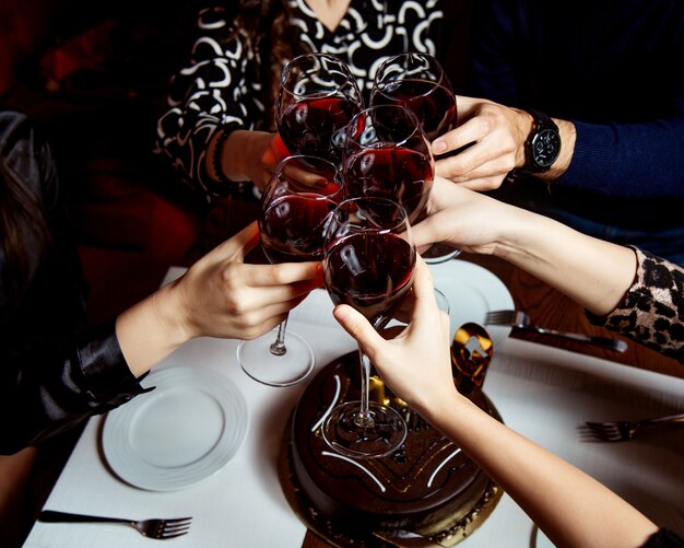 Raised glasses of red wine and chocolate cake