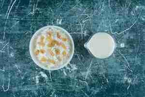 Free photo raisins on a bowl of rice pudding next to a glass of milk, on the blue table.