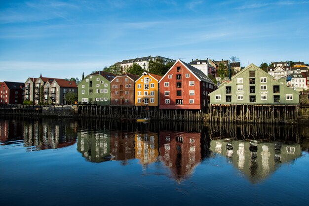 Range of buildings on the shore reflecting in the lake under the clear blue sky