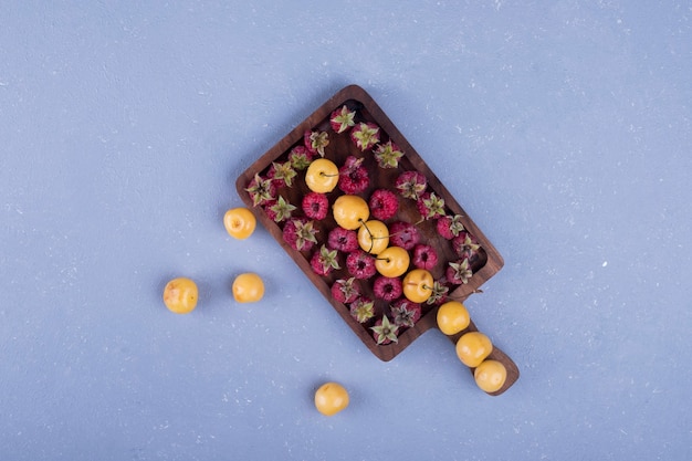 Raspberries and cherries in a wooden platter in the center