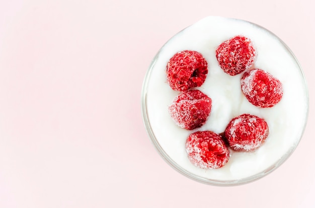 Raspberries in yogurt on pink background 