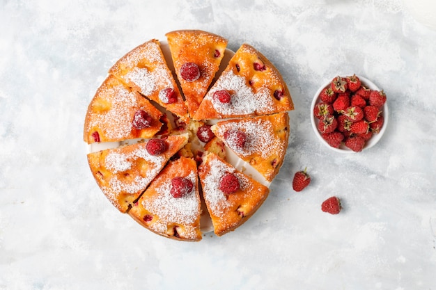Бесплатное фото Малиновый торт с сахарной пудрой и свежей малины на свет. летний ягодный десерт.