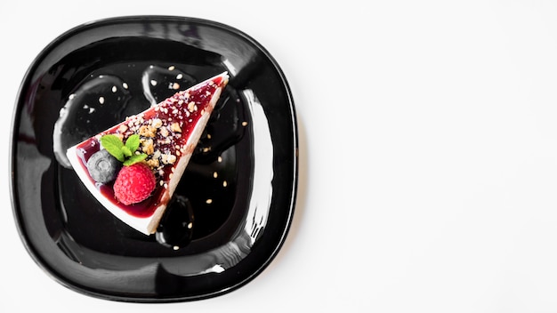 Raspberry and mint with cheesecake on black plate over white backdrop