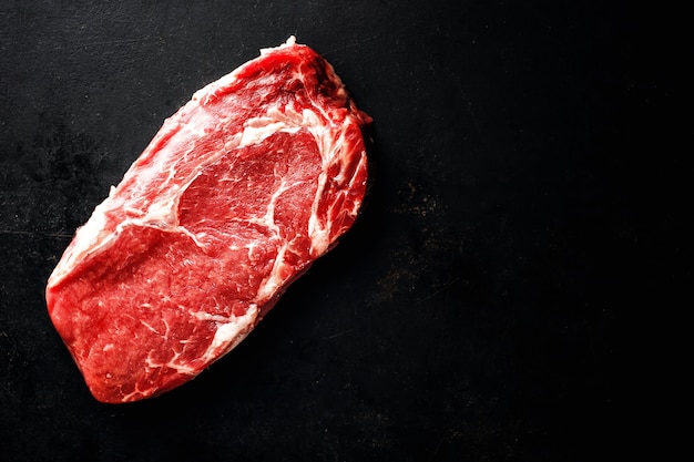 Raw beef steak on dark surface