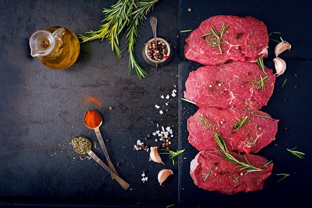 Raw beef steaks with spices and rosemary. Flat lay.Top view