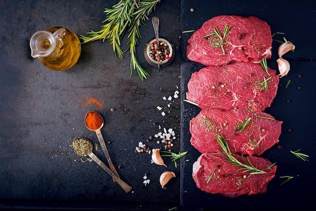 Raw beef steaks with spices and rosemary. Flat lay.Top view