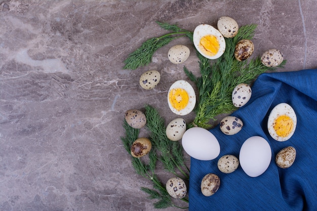 Free photo raw and boiled eggs with herbs on a blue towel