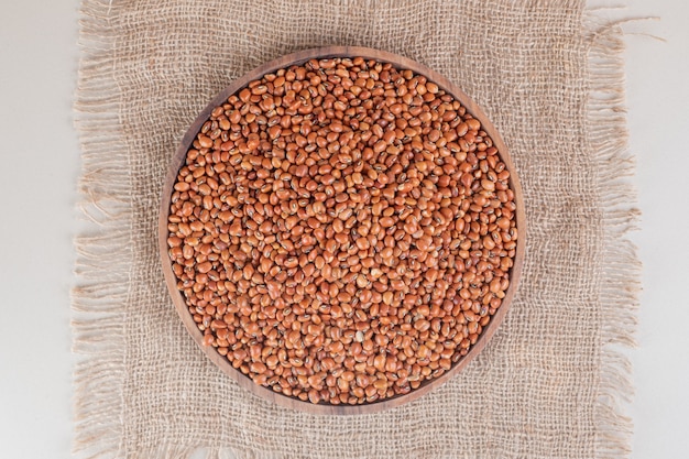 Raw brown beans on a wooden platter on concrete.