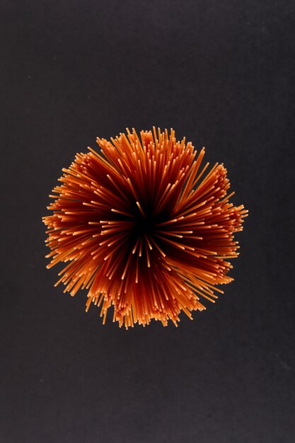 raw brown spaghetti pasta on black surface top view