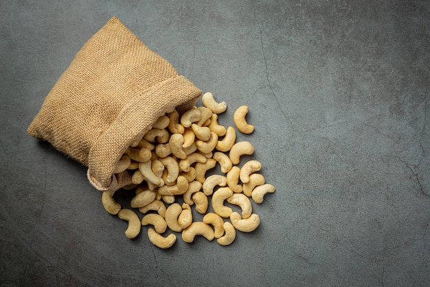 Raw cashews nuts in bag on dark background