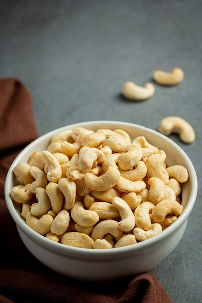 Raw cashews nuts in bowl on dark background