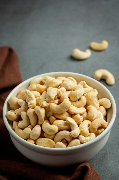 Raw cashews nuts in bowl on dark background