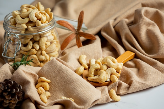 Raw cashews nuts in an open glass jar on marble background