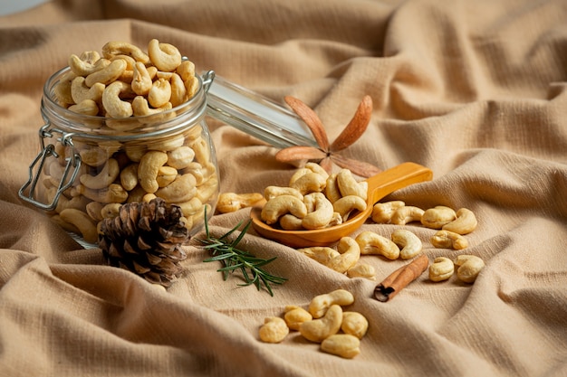 Raw cashews nuts in an open glass jar on marble background