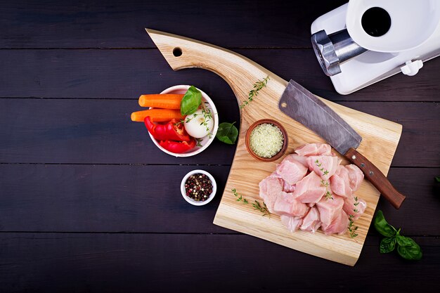 Raw chicken breast fillets on wooden cutting board with herbs and spices. Top view