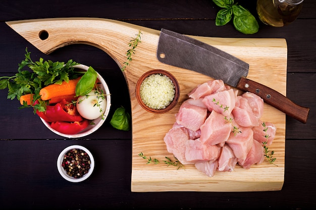 Raw chicken breast fillets on wooden cutting board with herbs and spices. Top view