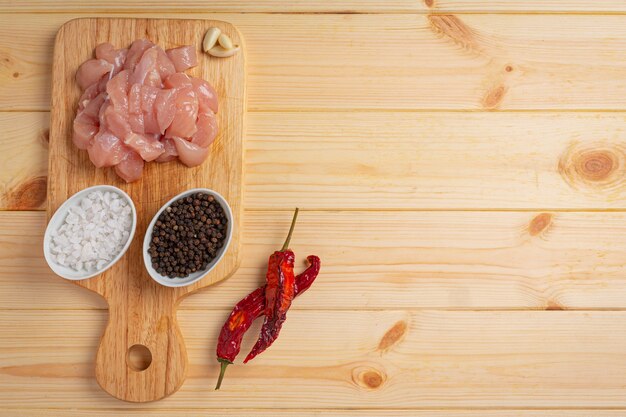 Raw chicken breast on the wooden surface.