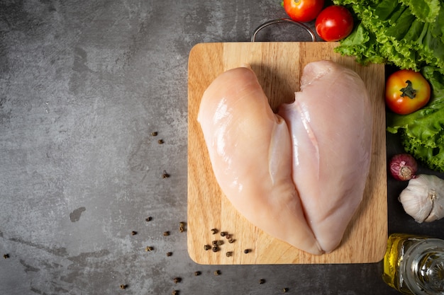 Raw chicken breasts on wooden cutting board.