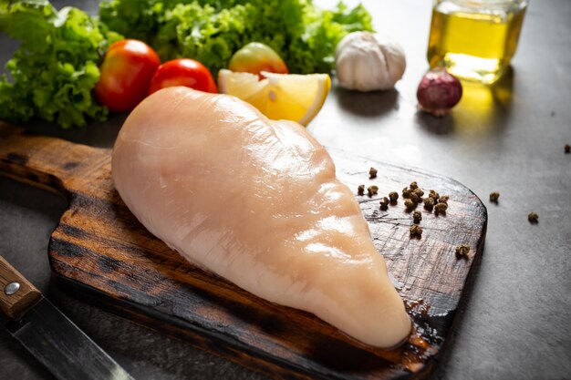 Raw chicken breasts on wooden cutting board.