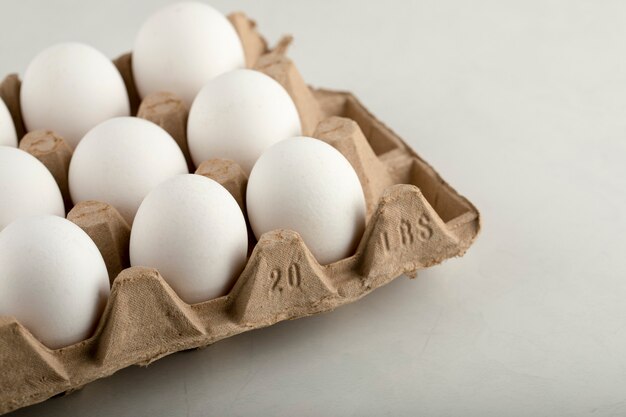 白い表面の卵ボックスに生の鶏卵。