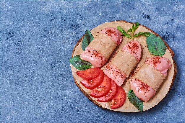 Raw chicken fillet with vegetables on a wooden board on blue