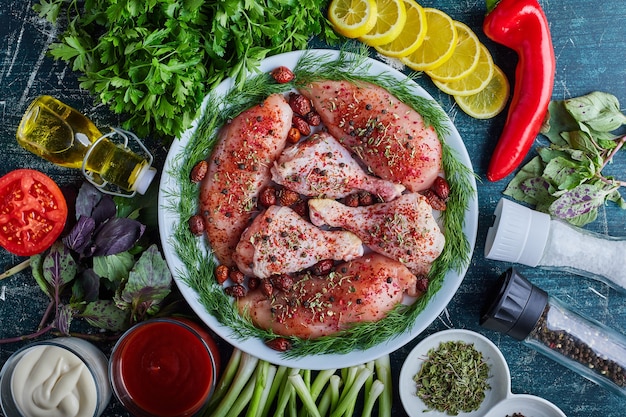 Бесплатное фото Сырые куриные окорочка и филе в зеленой тарелке.