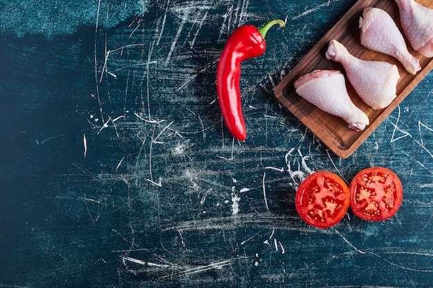 Raw chicken legs on a wooden board.