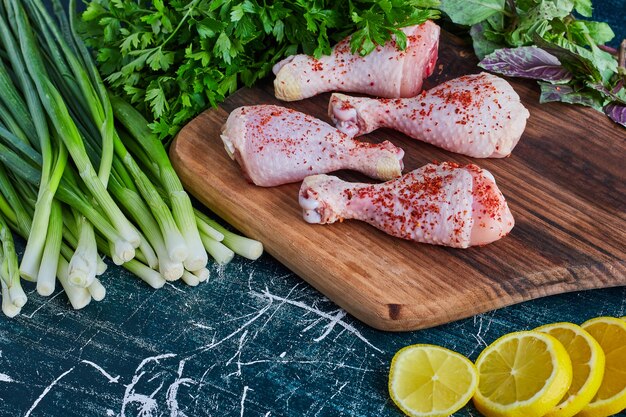 Raw chicken legs on a wooden platter.