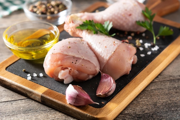 Raw chicken meat legs with spices and herbs on cutting board