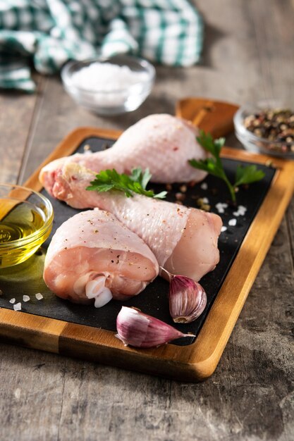 Raw chicken meat legs with spices and herbs on cutting board