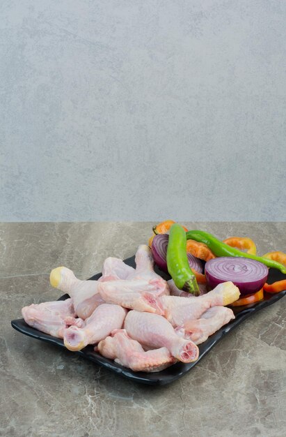 Raw chicken meat with peppers and onion on dark plate. High quality photo