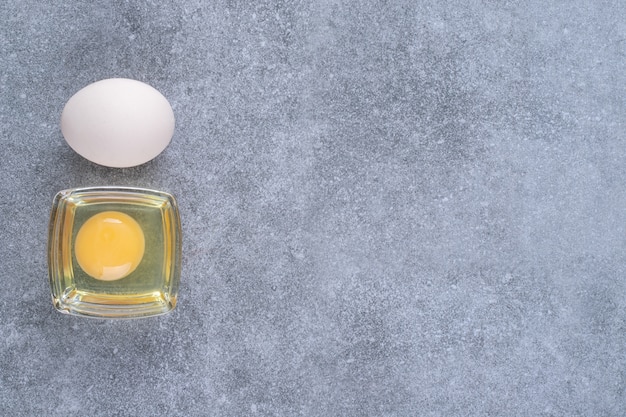 Raw chicken white egg with yolk on a marble surface