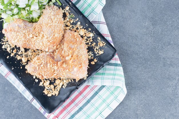 Raw chicken wing nuggets on black plate.