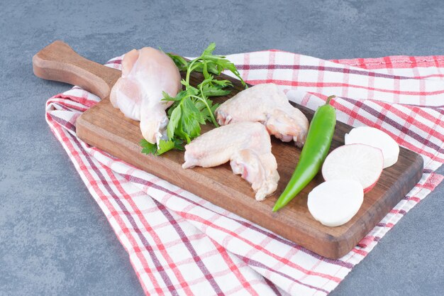 Free photo raw chicken wings and leg on wooden board.