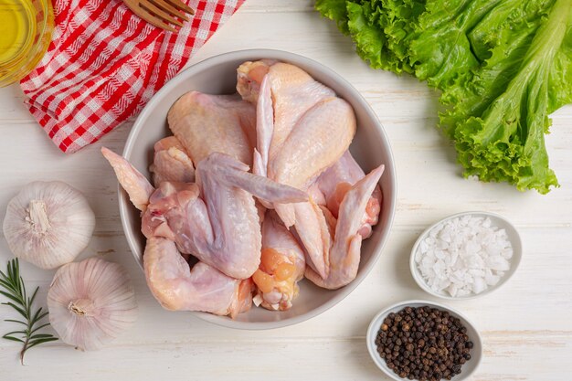 Raw chicken wings on the white wooden surface.