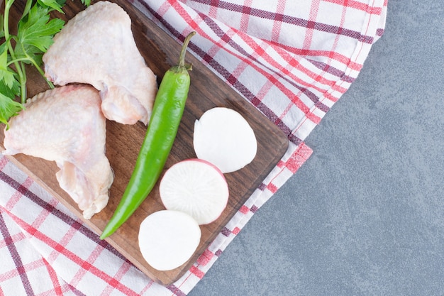 Raw chicken wings on wooden board.