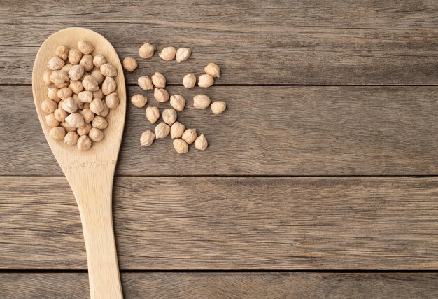 Raw chickpeas on a poon over wooden table with copy space.