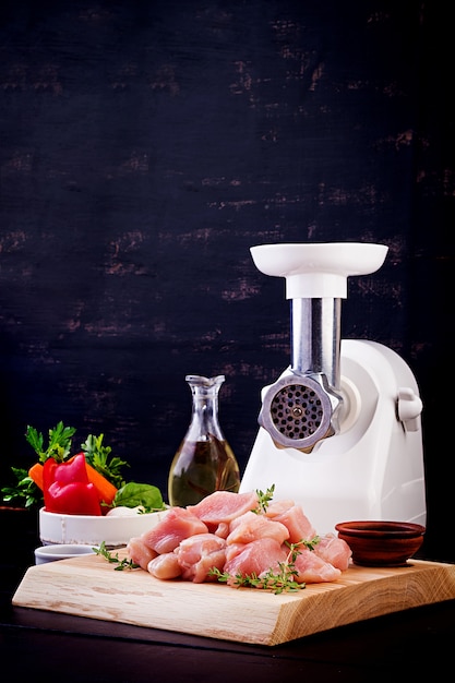 Raw chopped chicken breast fillets on wooden cutting board  and meat grinder. copy space