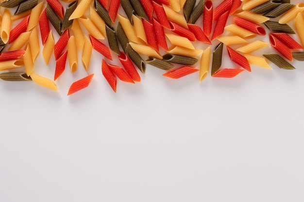 raw colored pasta green yellow and red penne pasta with copy space