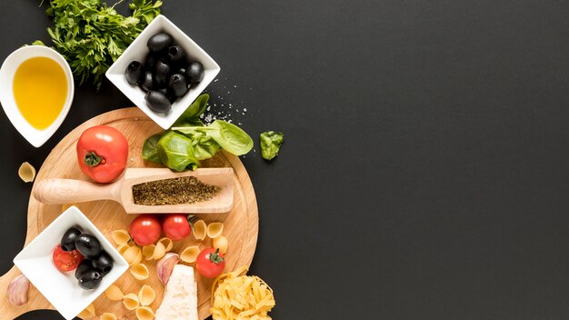 Raw conchiglie pasta with ingredient over black background