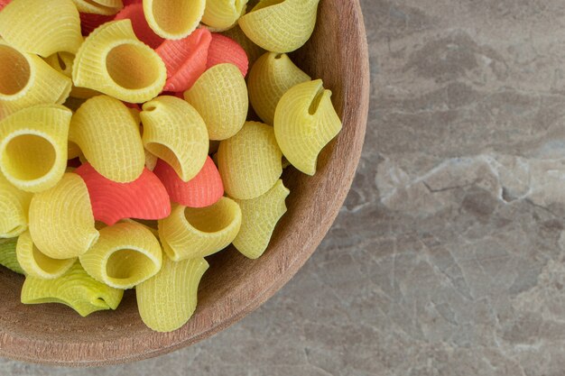 Raw conchiglie pasta in wooden bowl