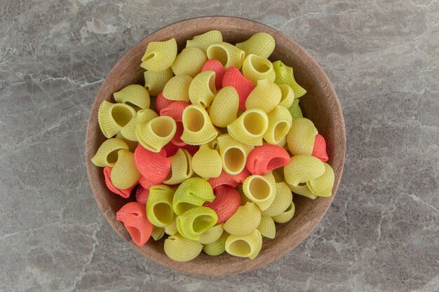 Raw conchiglie pasta in wooden bowl.