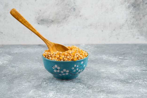 Raw corn kernels in blue bowl with spoon.