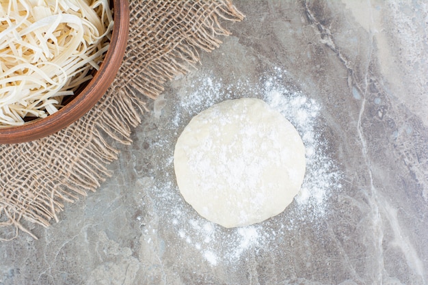 Foto gratuita pasta cruda e formaggio grattugiato su una pietra.